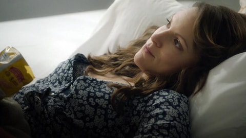 Une femme étendue sur un lit qui a un air rêveur.