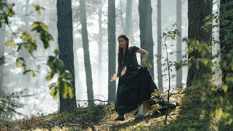 Sissi (Dominique Devenport) marche en forêt en montagne.