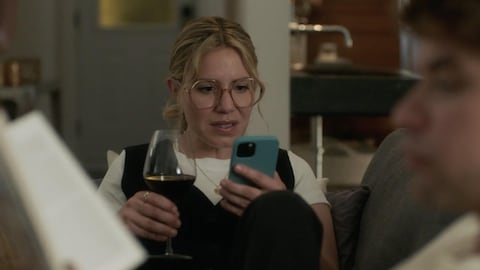 Sarah (Magalie Lépine-Blondeau) qui regarde son cellulaire, pendant que Lou lit un livre (Mikhaïl Ahooja), les deux assis sur le divan.