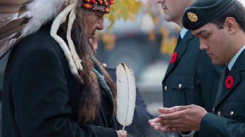 Un homme portant une coiffe traditionnelle autochtone et un autre dans son costume de vétéran.