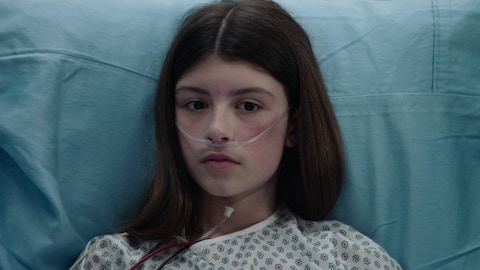 Une jeune patiente dans un lit d'hôpital.