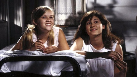 Deux jeunes filles (dont Reese Whiterherspoon) allongées sur le ventre sur un lit, côte à côte.