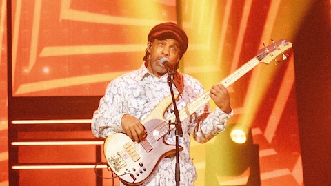 Le chanteur joue de la basse sur scène. 