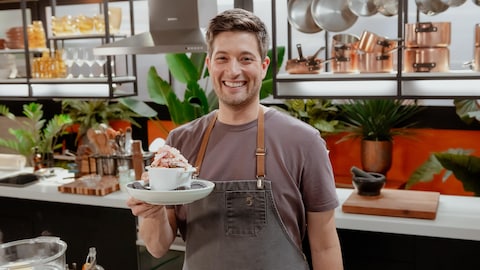 Vincent Dion-Lavallée pose dans la cuisine avec son plat à la main.