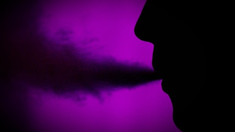 Gros plan de profil d'un jeune  vapoteur de cannabis avec la boucane qui lui sort de la bouche.