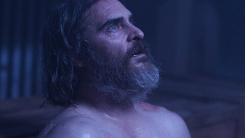 Un homme barbu et torse nu (Joaquin Phoenix) regarde en l'air, l'air effaré.
