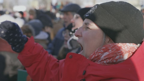 Une femme exprimant sa colère dans une foule.