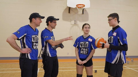 Les deux animateurs et les jeunes discutent. L'un d'eux tient un ballon de volleyball. 