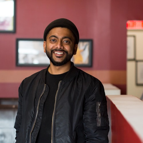 Aakash Patel sourit pour la caméra dans son restaurant.