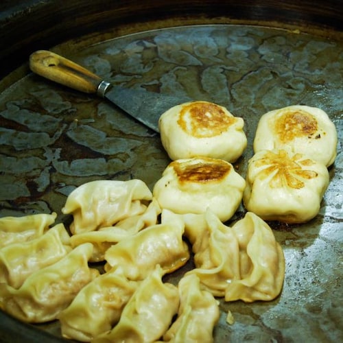 Des dumplings sont déposés sur une plaque chauffante.