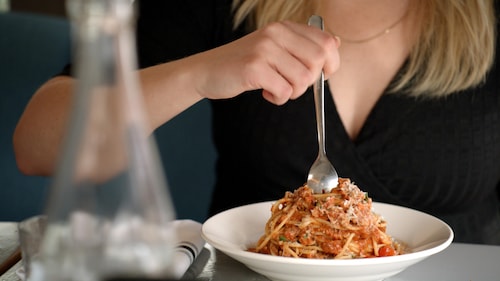 Une femme en train de manger une assiette de spaghettis.