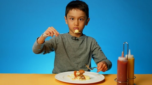 Un jeune garçon inquiet à l'idée de déguster son assiette de déjeuner gastronomique.