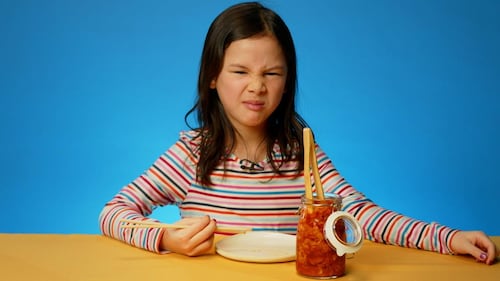 Une petite fille qui n'est pas certaine de vouloir goûter au kimchi.