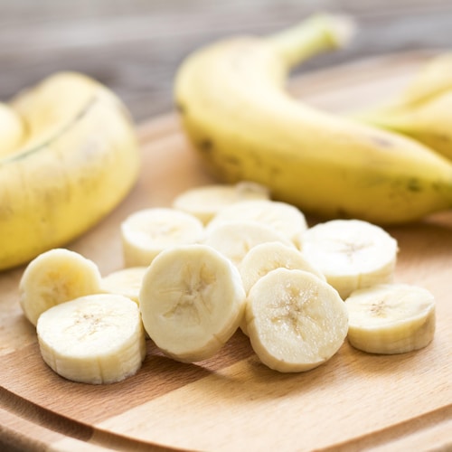Une banane coupée en morceaux sur une planche.
