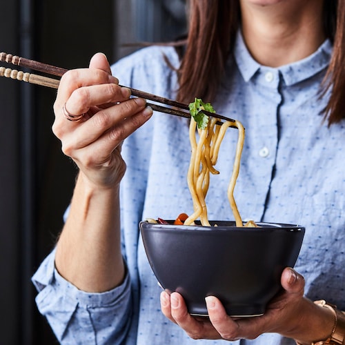 Femme qui tient un bol de nouilles udon.