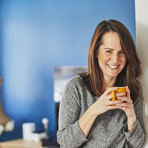 Geneviève O'Gleman tient une tasse à la main et sourit à la caméra. 