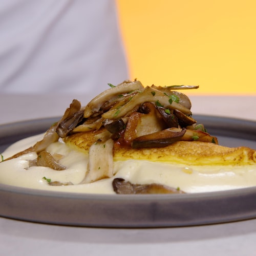 Une omelette soufflée au fromage garnie de champignons sautés, servie dans une assiette.
