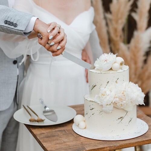 Un homme et une femme en train de couper leur gâteau de mariage.