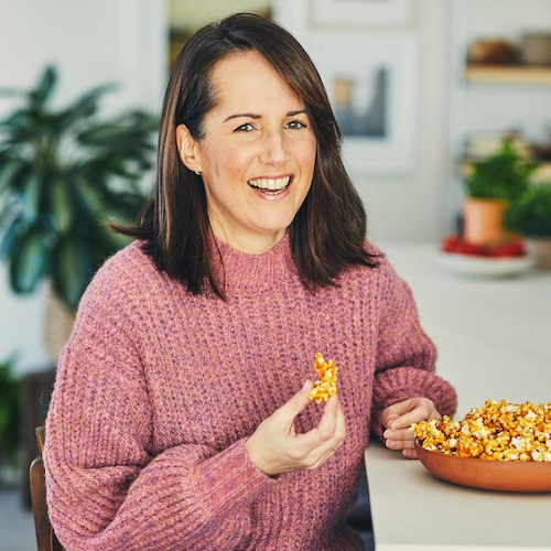 La nutritionniste Geneviève O'Gleman est assise sur une chaise au comptoir et elle tient du popcorn dans sa main.