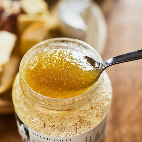 Une cuillère dans un pot de miel qui a commencé à se cristalliser.