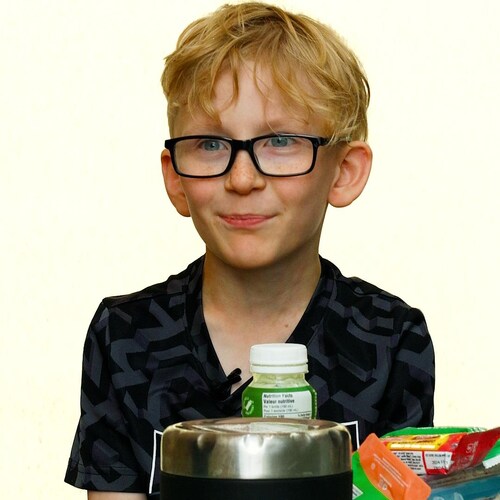 Un petit garçon avant le contenu de son lunch devant lui.