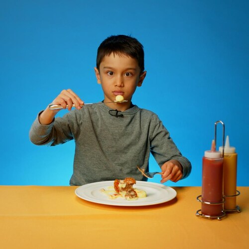 Un jeune garçon inquiet à l'idée de déguster son assiette de déjeuner gastronomique.