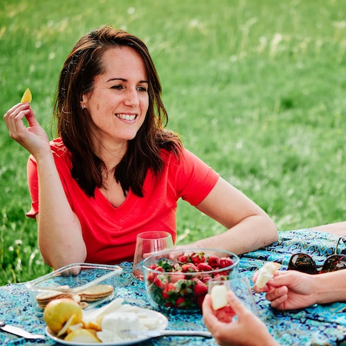 La nutritionniste Geneviève O'Gleman est assise sur une table à pique-nique avec un morceau de poire à la main.