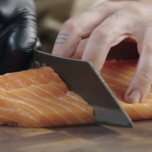 Une personne coupe le saumon pour en faire un pavé. 