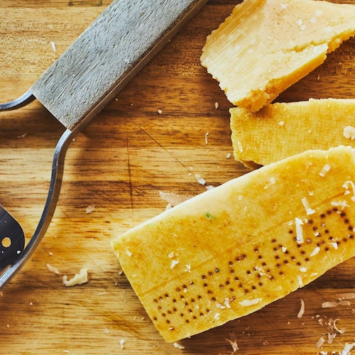 Morceaux de croute de fromage parmesan avec une râpe.