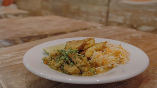 Une assiette ronde contient du lambi, du riz et un quartier de lime. Le plat est posé sur une table du restaurant. 