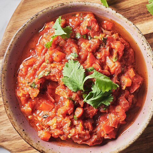 Un bol de salsa garni de coriandre fraîche et servi avec des nachos.