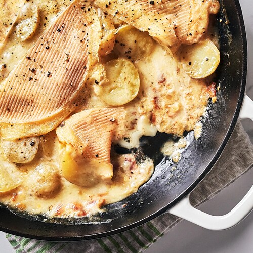 Une casserole remplie de tartiflette et une portion de tartiflette dans une assiette.