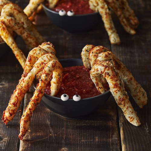 Trois araignées au parmesan avec des yeux sont sur une table en bois.