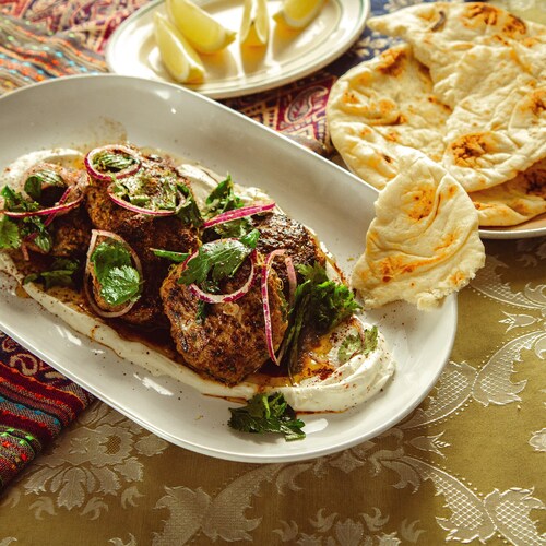 Des boulettes d'agneau kefta servies sur une sauce au yogourt.
