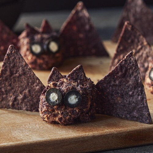 Quatre chauves-souris au fromage sont sur une planche de bois.