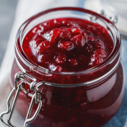 Un pot en verre rempli de chutney aux fruits rouges.