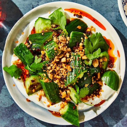 Des concombres dans une assiette avec du yogourt, de la coriandre et des arachides.