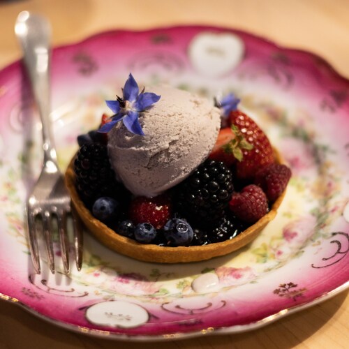 Un boule de crème glacée au miel et à la lavande posée sur une tartelette aux fruits.