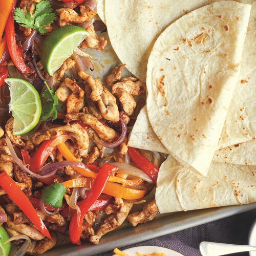 Des fajitas, du poulet et des légumes sur une plaque.