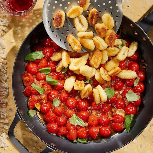 Une poêle remplie de tomates cerises et de gnocchis.