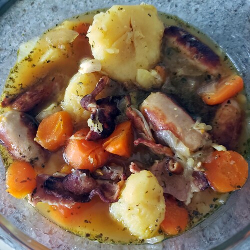 Un plat de ragoût de pommes de terre, de bacon et de saucisses.
