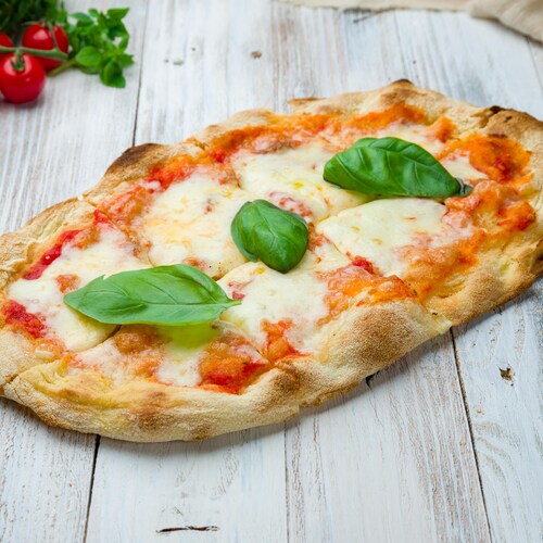 Une pizza au fromage avec des feuilles de basilic sur le dessus.