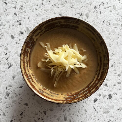 Un bol de potage servi avec du fromage râpé.
