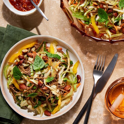 De la salade de bok choys, de chou et de soba dans des assiettes et un bol de service.