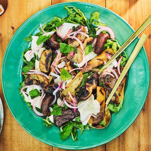 Une salade de champignons, de mozzarella et d'oignons marinés dans une assiette de service.