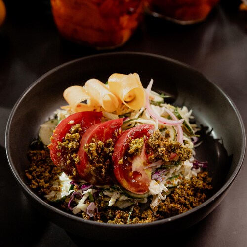 Un bol de salade de chou garnie de croustillant de falafels, de tomates et de légumes marinés.