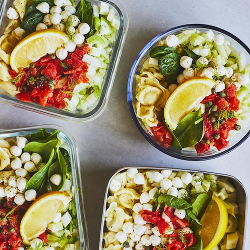 Quatre pots contenant une salade de tortellinis au saumon fumé sur un comptoir gris.
