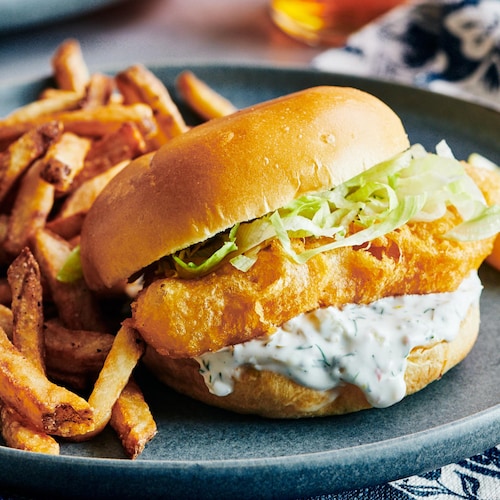 Un sandwich fish and chips dans une assiette avec des frites.