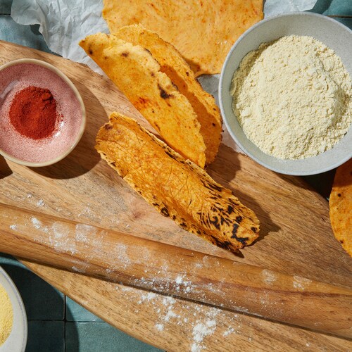 Sur une planche à découper se trouvent des tacos au maïs.