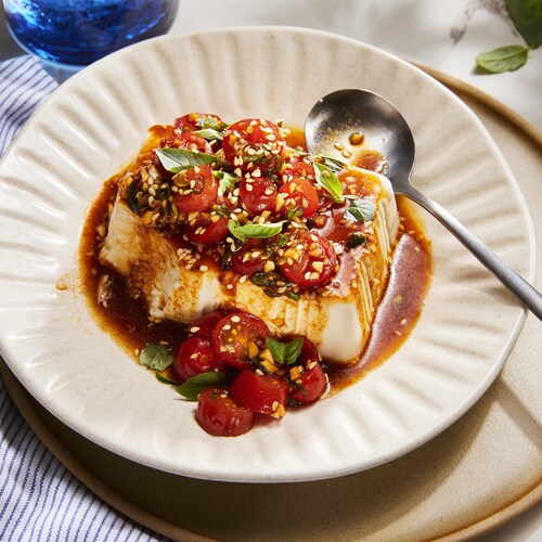 Une assiette de tofu soyeux aux tomates et au basilic avec une cuillère.